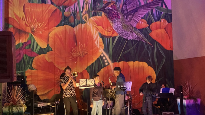 A large mural with hummingbird and orange poppies while jazz musicians play
